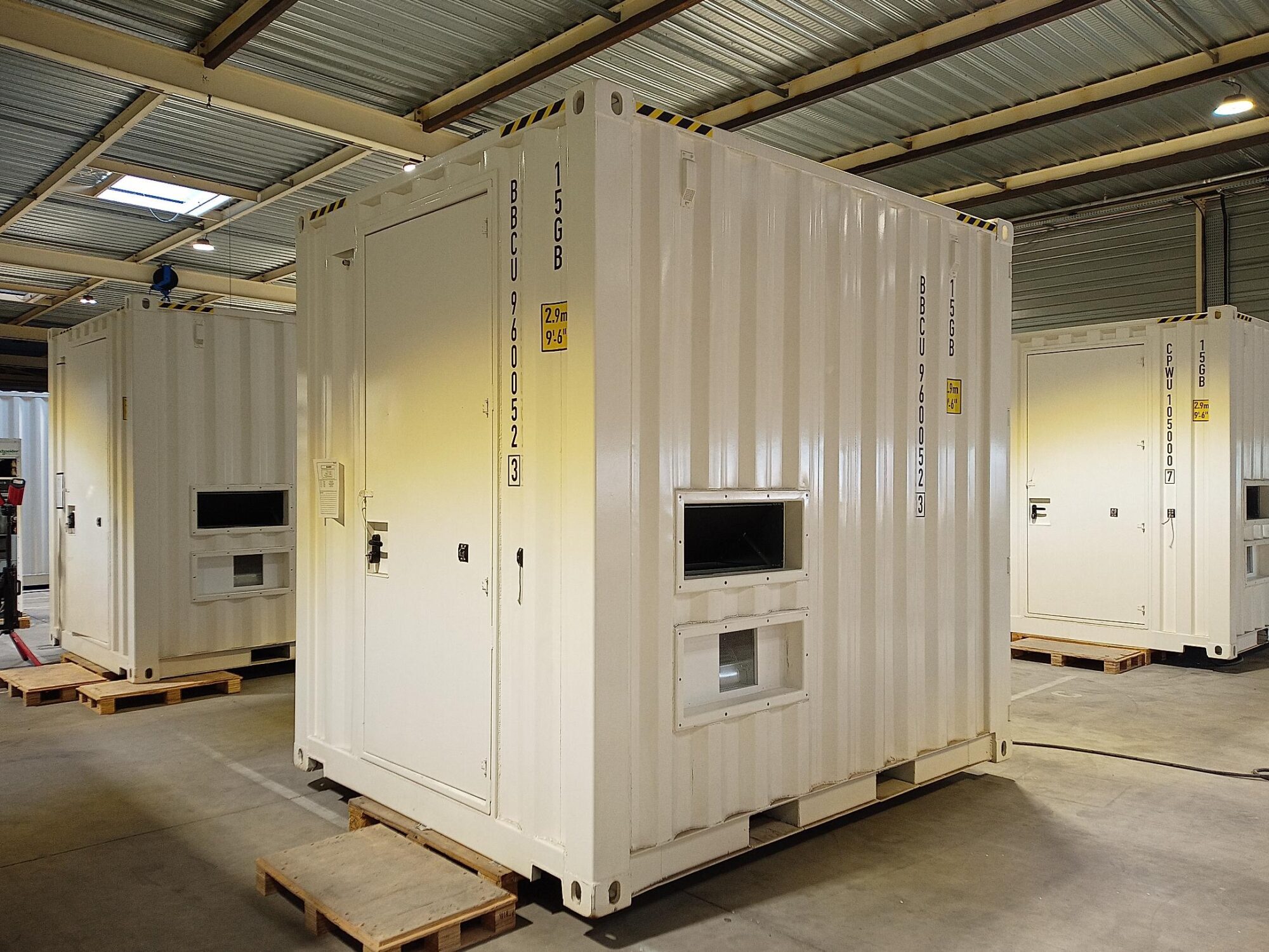 Plusieurs containers techniques blancs en cours de fabrication dans l’atelier ZK-Systems, destinés à des applications télécom