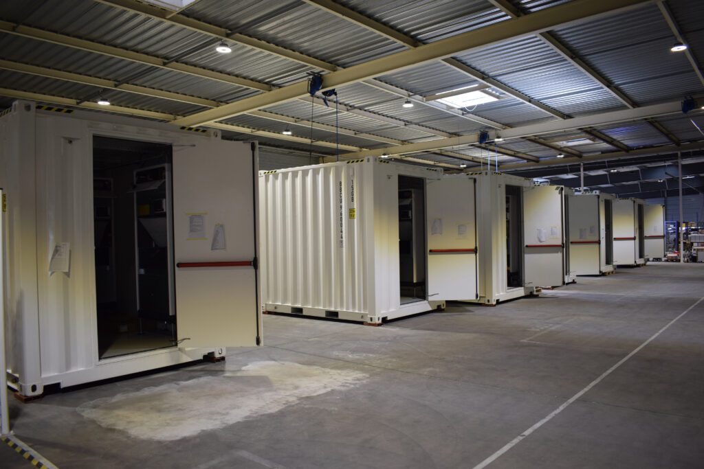 Stations télécom conteneurisées en cours d’intégration dans l’atelier de production de ZK-Systems, portes ouvertes sur les équipements.