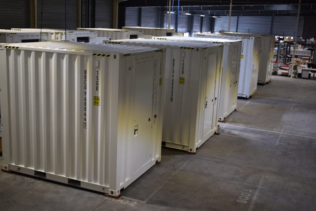 Rangée de conteneurs techniques modulaires blancs alignés dans un atelier industriel moderne de ZK-Systems.