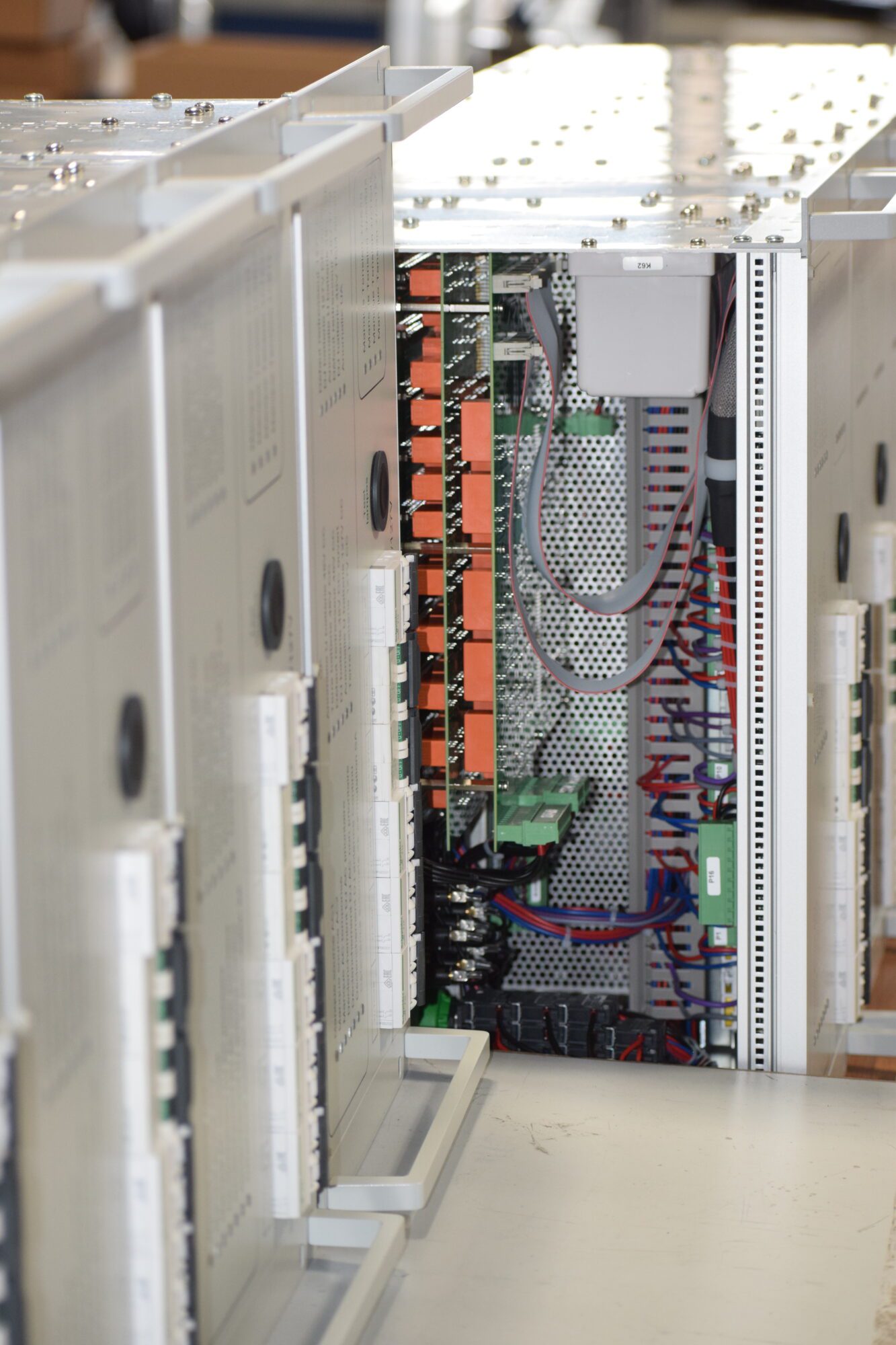 Focus sur la structure interne d’un module électronique, révélant les connecteurs, relais orange, câblages et borniers dans un environnement technique propre.
